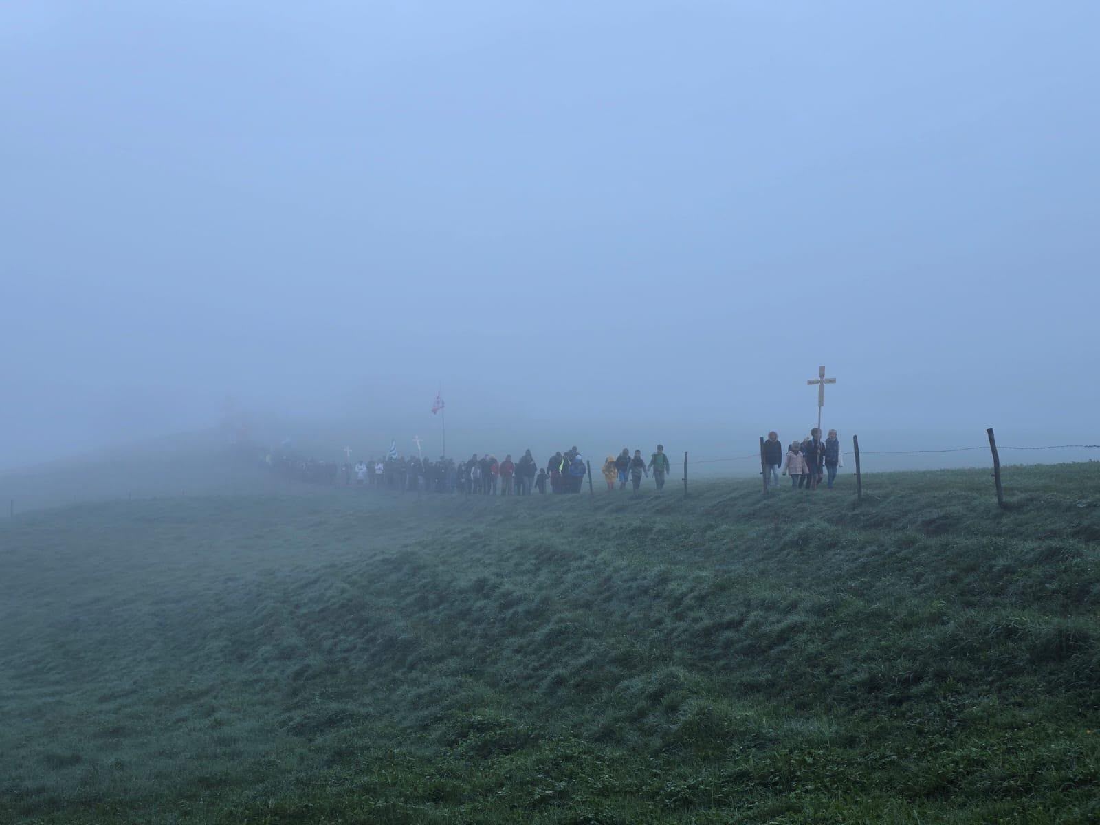 Pèlerins traversant un pré dans la brume